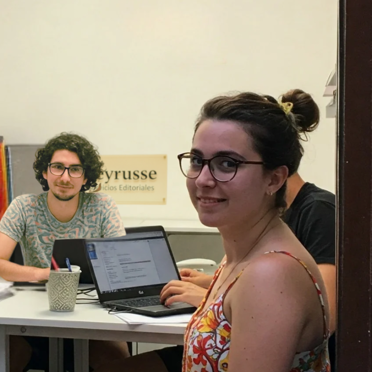 Equipo de trabajo reunido en la oficina de Peyrusse Servicios Editoriales, frente a portátiles y materiales de edición.
